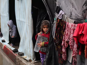 طفلان نازحان أمام مسكنيهما المؤقتين في غزة. تصوير اليونيسف/البابا