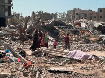 أشخاص يتواجدون وسط منطقة مدمرة في خانيونس. تصوير مكتب الأمم المتحدة لتنسيق الشؤون الإنسانية، 17 نيسان/أبريل 2024