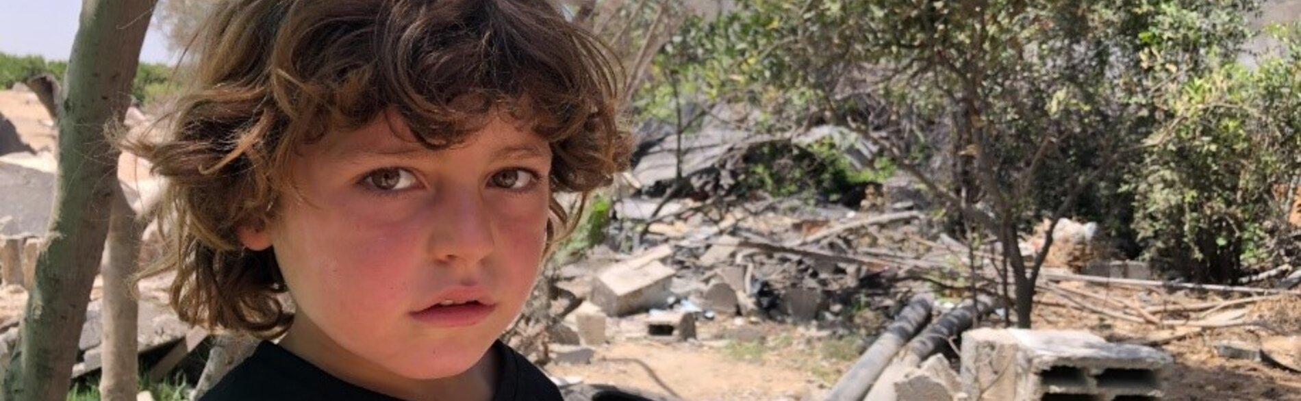 A child in Gaza beside a destroyed structure from the May escalation, 9 June 2021. Photo by OCHA