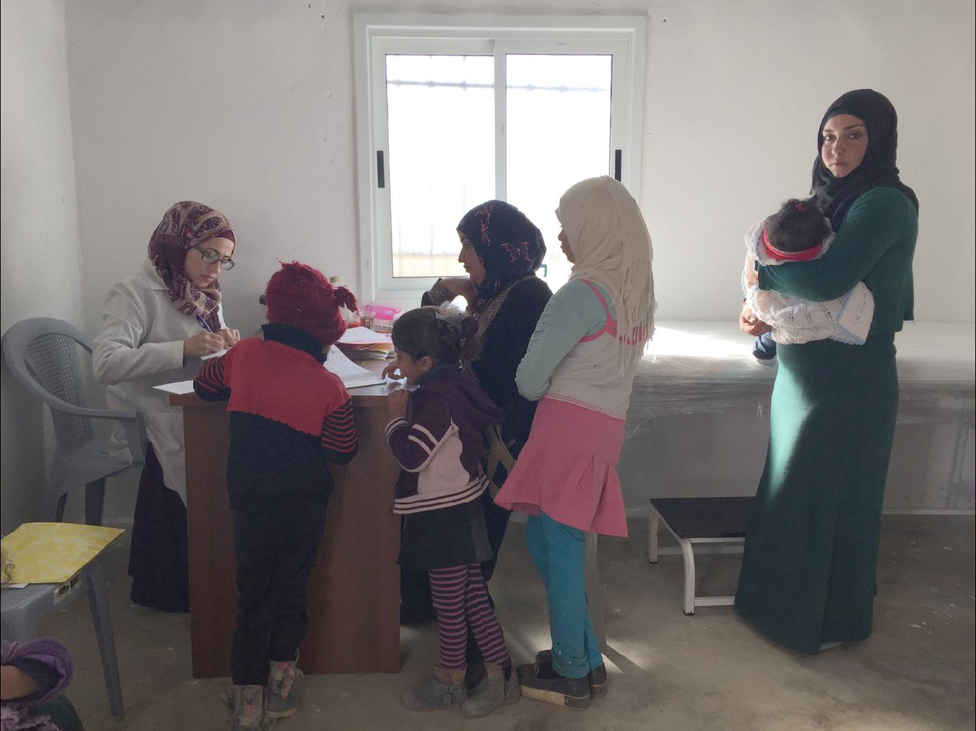 Amal and her sister-in-law and their children receiving treatment at al Mirkez mobile clinic. Photo by OCHA