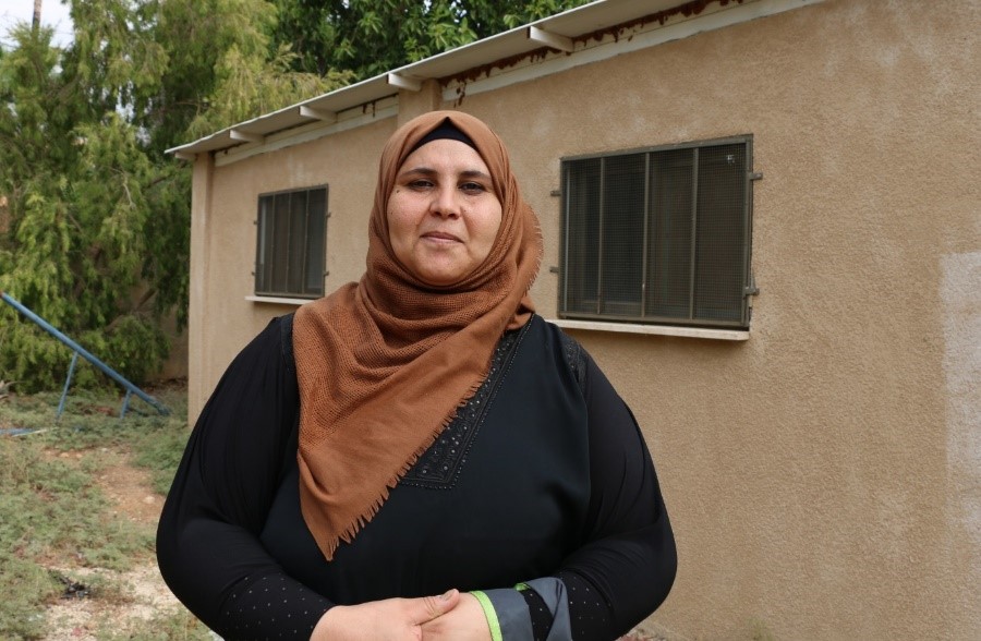 Ghada Abu Gheesh from Furush Beit Dajan. The building behind serves as a mobile clinic, for just two days a week. Credit: WHO/Alice Plate