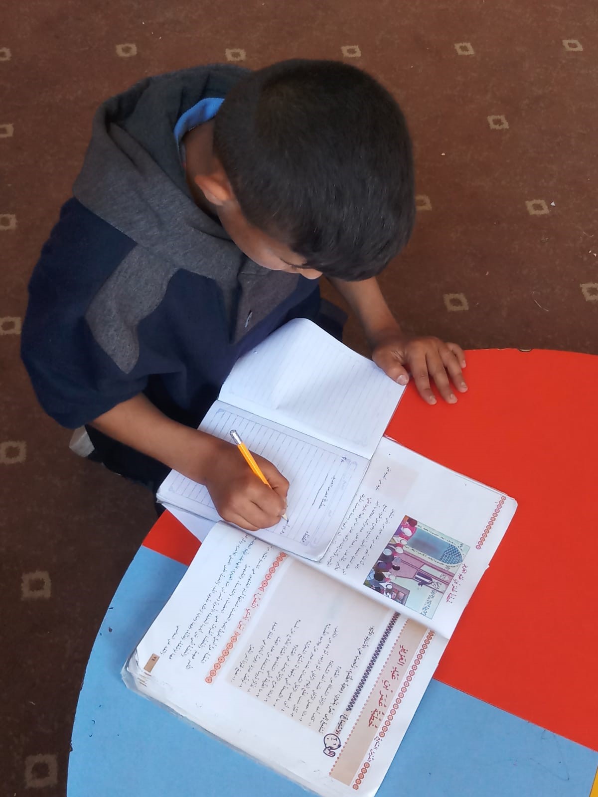 Abdallah reviewing his homework at Tdh Protection centre. © Photo by Terre des hommes