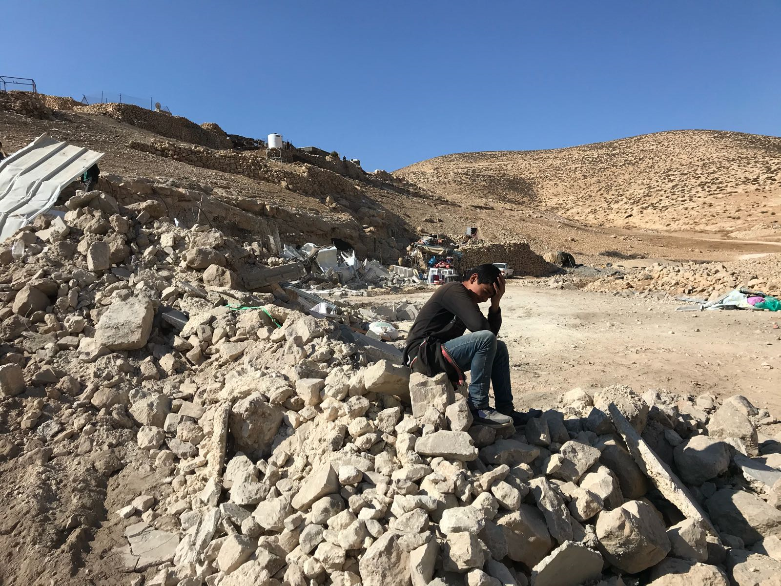 Young boy in front of his demolished home in Maghayir al Abeed (Hebron), 5 December 2019. © Photo by OCHA.
