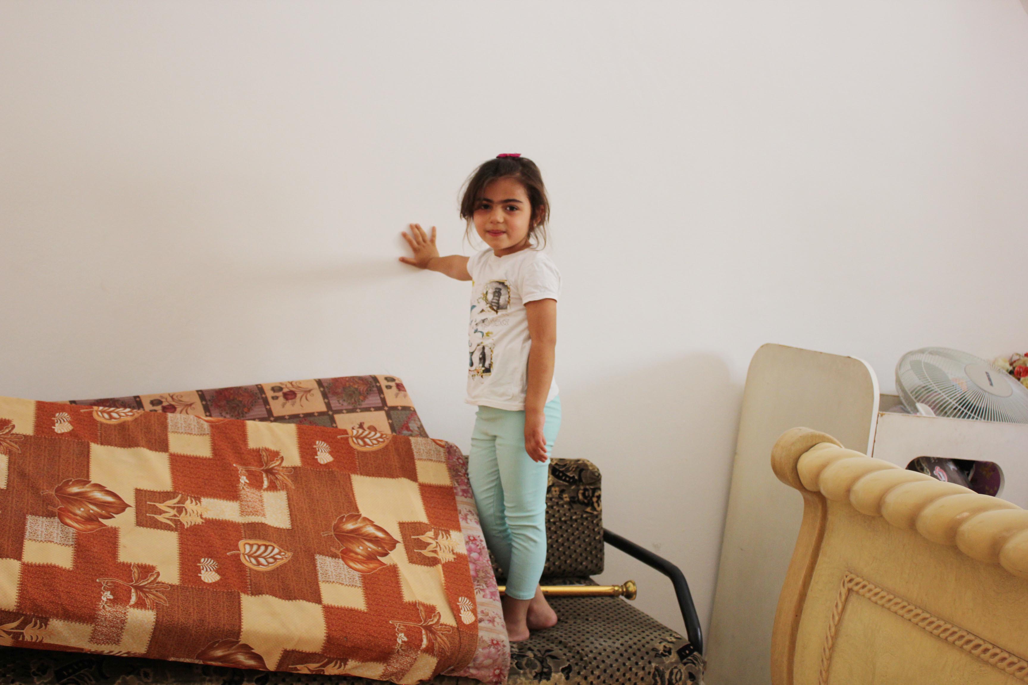 Suhad’s daughter, Muluk (4 years old), standing in her repaired bedroom.