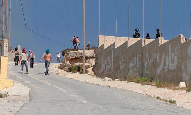 مستوطنون إسرائيليون، يرافقهم جنود إسرائيليون، وهم يهاجمون قرية عوريف (نابلس)، 6 تموز/يوليو 2018 © - تصوير عادل العامر/بتسيلم