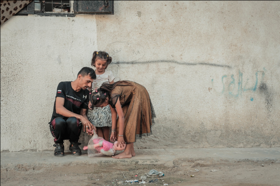 Rimas, 7, and Layan, 11, play with their father Medhat, 33, outside their home in Jabalia on 21 August 2019. ©  Photo by Ahmed Mashharawi, NRC
