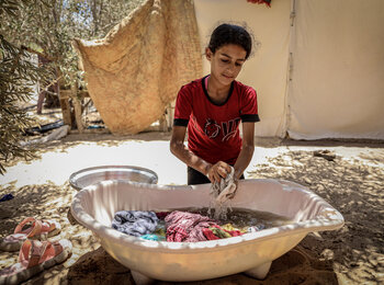 A displaced girl washing clothes in a refugee camp in Khan Younis. Photo by WHO 