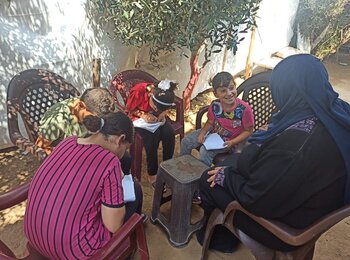 Ghada and her children sitting on the newly bought plastic chairs, September 2020. Photo by SIF