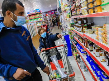 Jaber and his daughter select the groceries they need most, for which they would pay with an CRS electronic voucher. Photo by Mohamed Reefi for CRS