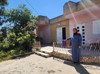 Umm Saleh Shreteh standing in front of her house in Al Mazra’a Al Qibliya, the central West Bank. Photo by OCHA Umm Saleh Shreteh standing in front of her house in Al Mazra’a Al Qibliya, the central West Bank. Photo by OCHA