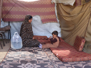 Suad* giving clean water to her three-year-old son Rasheed*