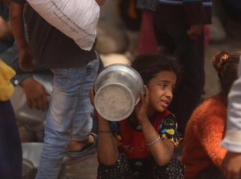 A Palestinian girl waiting for food served by a community kitchen in Gaza city. Photo by UN News