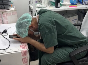 An overwhelmed medical worker in Gaza rests his head in his hands. Photo by Médecins Sans Frontières