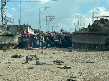 Displaced Palestinians squeezed between two tanks. They are waiting their turn to cross an Israeli checkpoint leading to Rafah governorate, southern Gaza, as hostilities continue in Khan Younis and following evacuation orders. Photo by OCHA/Olga Cherevko