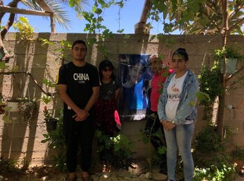 Kamal and three of his children. On the wall is a photo of his son Ibrahim who was killed in the escalation of 2008/09. Beit Lahiya, 7 July 2021. Photo by OCHA.