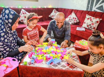 أسماء وسعدي يلعبان مع بنتيهما في غرفة معيشتهم التي أعيد ترميمها