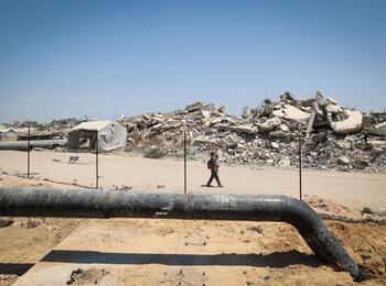 Children walk past wastewater infrastructure under repair in Gaza, in an area destroyed by hostilities. Photo by UNICEF
