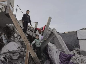 Reda, 12, and Siraj, 5, standing on a makeshift staircase leading up to the roof of their damaged home in Jabalya refugee camp. Photo by ©UNICEF-SoP/2025/Mohammed Nateel