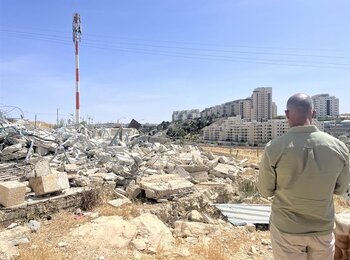 رجل فلسطيني مهجَّر من قرية أم طوبا في القدس الشرقية يطلّ على مستوطنة هار حوما الإسرائيلية القريبة بعدما هدمت القوات الإسرائيلية منزله. تصوير مكتب الأمم المتحدة لتنسيق الشؤون الإنسانية