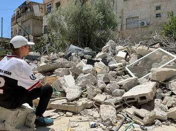 Palestinian boy sitting in front of a home demolished by its owners following Israeli orders in Silwan area of East Jerusalem. Photo by OCHA
