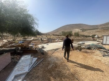 פלסטיני חולף על פני מה שנותר מהמבנים שהוא ושכניו נאלצו לפרק בקהילת הרועים אבזיק שבנפת טובאס, לאחר שגל מתקפות מתנחלים אילץ אותם לעבור למקום אחר. צילום: משרד האו"ם לתיאום עניינים הומניטריים