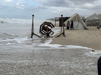 فلسطينيون نازحون في موقع مؤقت في المواصي بخانيونس، حيث غُمرت خيامهم بمياه الأمطار وموجات المدّ العالية عشية يوم 25 تشرين الثاني/نوفمبر 2024. تصوير مكتب الأمم المتحدة لتنسيق الشؤون الإنسانية 