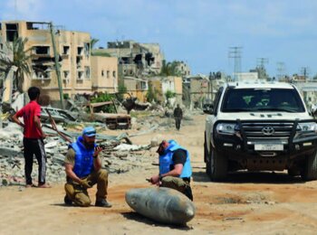 A UN team inspects an unexploded 1,000-pound bomb lying on a main road in Khan Younis. Photo: OCHA/Themba Linden.