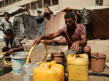 Jameel filling water containers at a displacement site in western Gaza in 2025. Photo by Mosab Alborno/Alef Multimedia, Oxfam, 22 September 2025.
