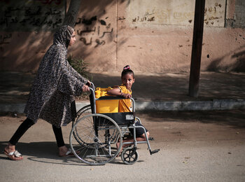 Palestinian girls use a wheelchair to carry water in Khan Younis city, in the southern Gaza Strip. Photo by UNICEF/Eyad El Baba 
