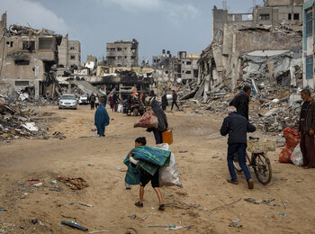 Displaced people carrying their belongings through the rubble of destroyed houses in Khan Younis, in the southern Gaza Strip, as they seek refuge. Photo: UNICEF/El Baba