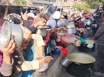 Women and girls in Rafah, southern Gaza Strip, holding pots and other empty containers in front of a group of volunteers preparing soup for displaced families. On 22 December, the Secretary-General warned that ”widespread famine looms,” following the Integrated Phase Classification (IPC) Special Briefs produced by the IPC global initiative on Gaza. Screenshot from a video by UNICEF