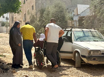 An elderly Palestinian woman in a wheelchair navigates a destroyed street in Jenin on her way to a hospital, following a ten-day operation by Israeli forces. Photo by OCHA, 8 September 2024 