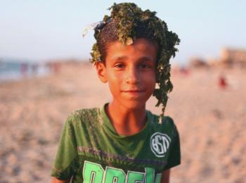 فتى فلسطيني بعد أن سبح على شاطئ ملوث في مخيم دير البلح للاجئين، غزة © - تصوير رهف بطنيجي، منظمة أوكسفام، 2018