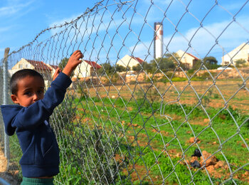 Mohammed, Aziz's 6-year-old son, stands next to their small vegetable garden in Um al Kheir, June 2015. Photo by WFP/Colin Kampschoer