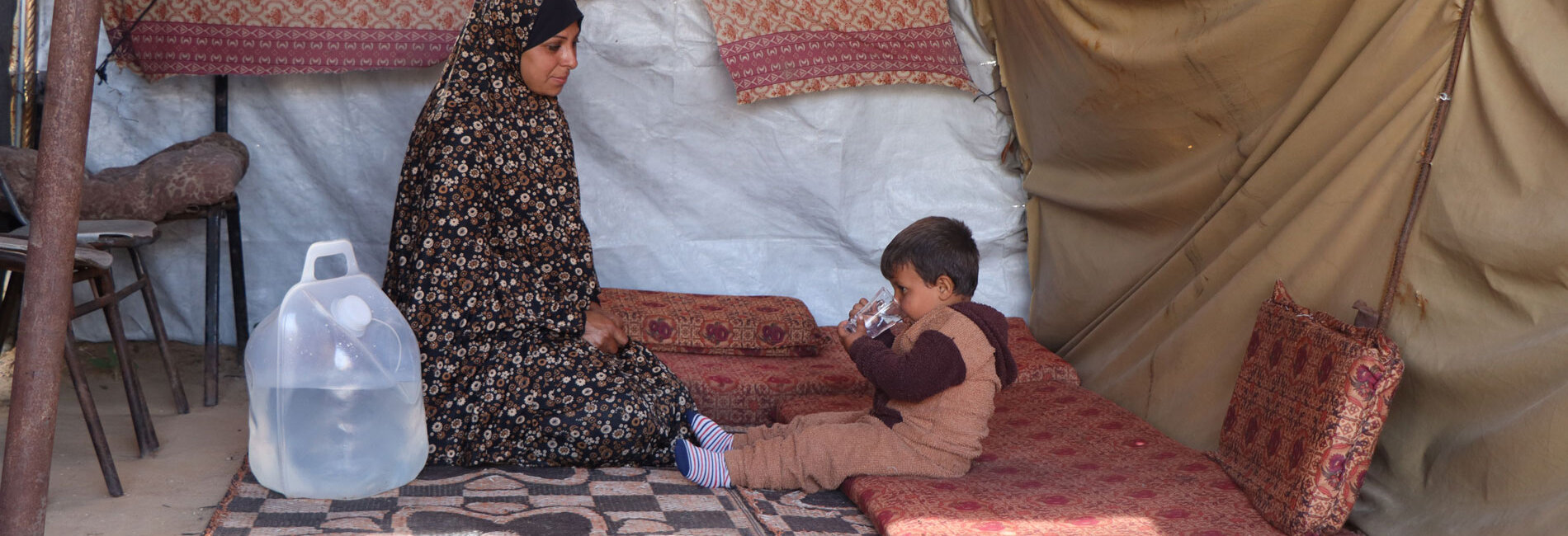 Suad* giving clean water to her three-year-old son Rasheed*
