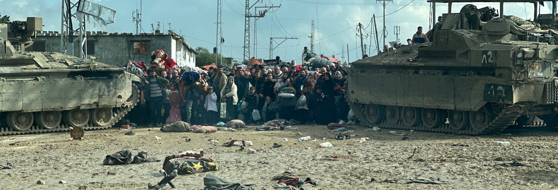 Displaced Palestinians squeezed between two tanks. They are waiting their turn to cross an Israeli checkpoint leading to Rafah governorate, southern Gaza, as hostilities continue in Khan Younis and following evacuation orders. Photo by OCHA/Olga Cherevko