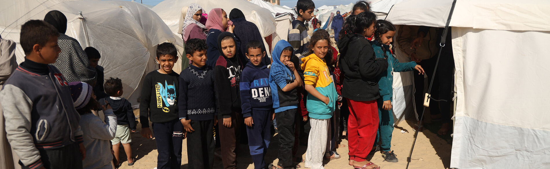 ילדים בכניסה למרפאה באוהל ברפיח, ממתינים בתור לבדיקות סקר לתת-תזונה ולהפנייה לטיפול, ככל שיידרש. צילום: יוניסף / אל-באבא