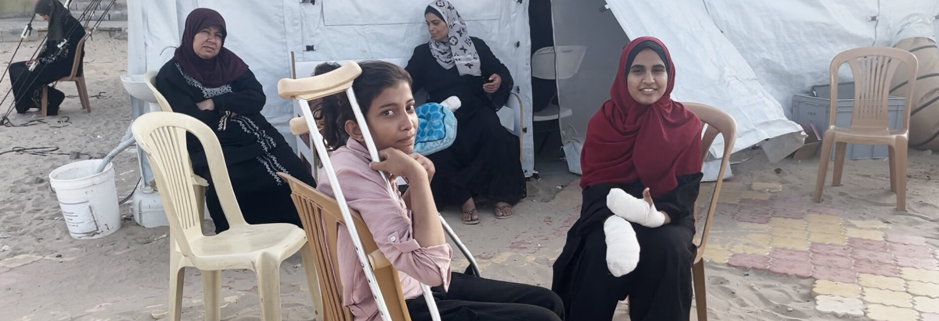 Girls sitting at a field hospital run by International Medical Corps after receiving medical treatment for injuries sustained in a 26 May strike on a site for displaced people in Rafah. Photo by OCHA/Yasmina Guerda, 27 May 2024