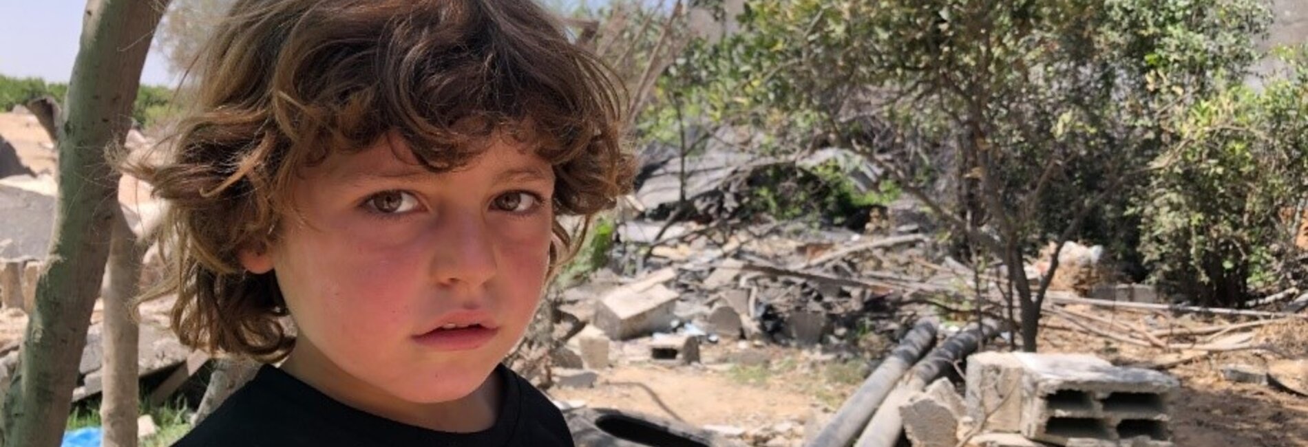 A child in Gaza beside a destroyed structure from the May escalation, 9 June 2021. Photo by OCHA