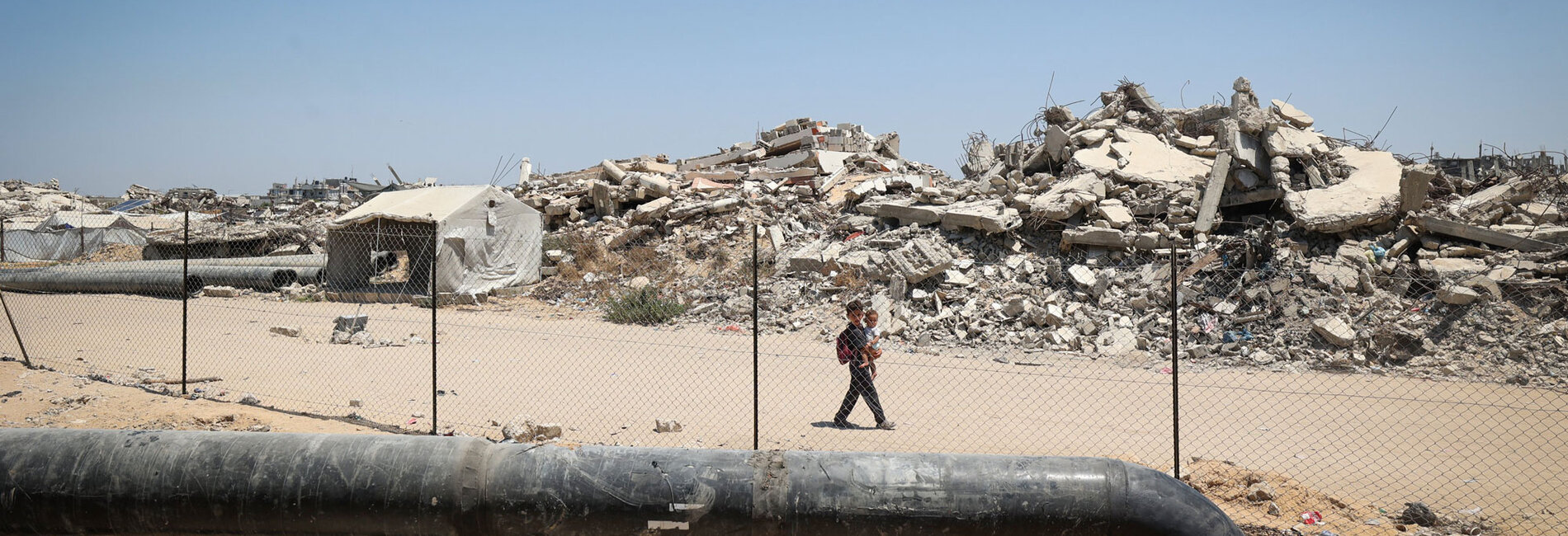 Children walk past wastewater infrastructure under repair in Gaza, in an area destroyed by hostilities. Photo by UNICEF