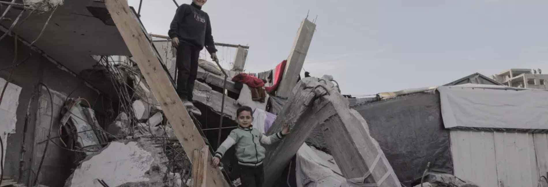 Reda, 12, and Siraj, 5, standing on a makeshift staircase leading up to the roof of their damaged home in Jabalya refugee camp. Photo by ©UNICEF-SoP/2025/Mohammed Nateel