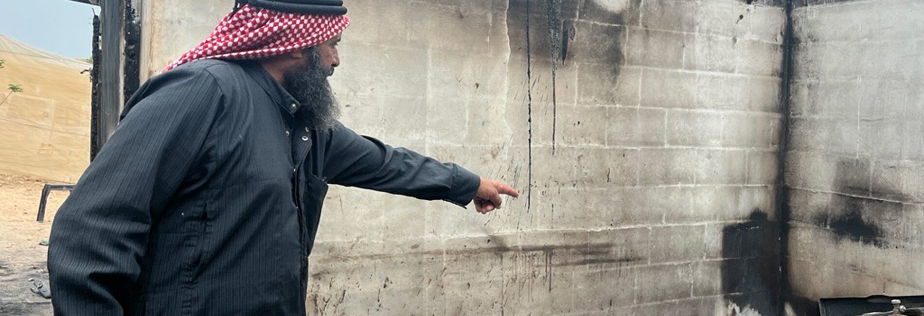 A resident of the Palestinian village of Bardala points to his home, which was torched by Israeli settlers. The arson destroyed houses and animal shelters, displacing two families and undermining livelihoods. Photo by OCHA