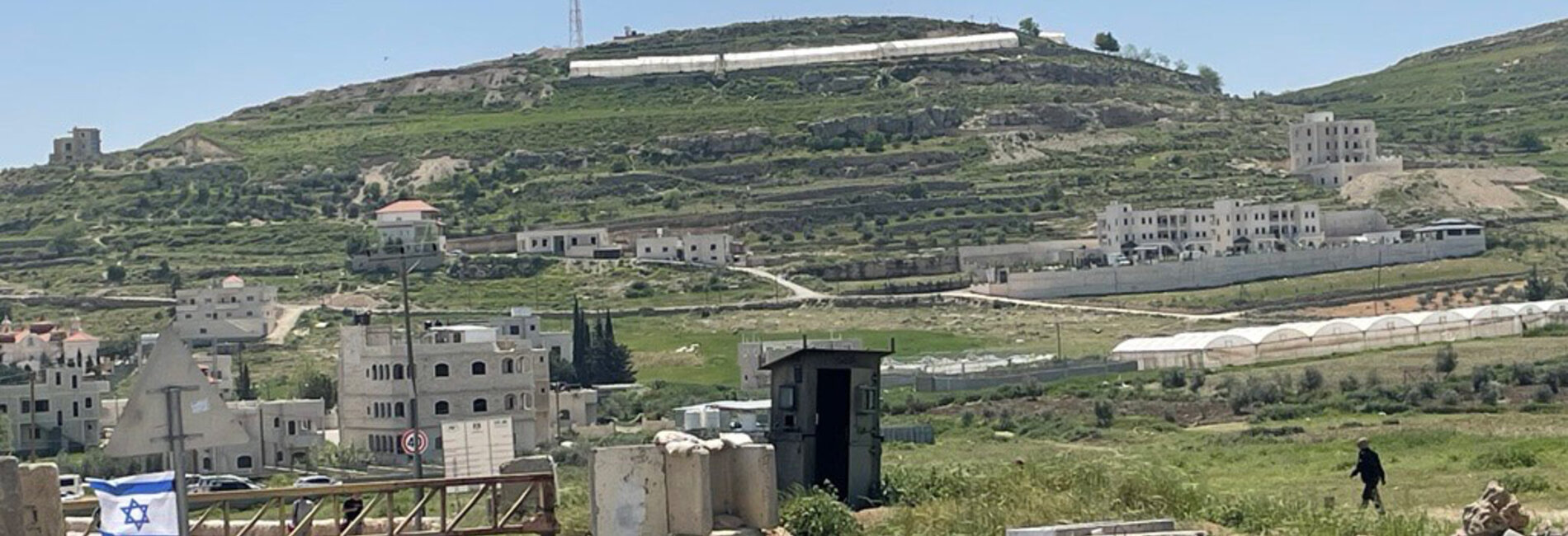 A Palestinian walking by a closed iron gate installed by Israeli forces to block a road leading to Al Fawwar camp, in the southern West Bank. Photo by OCHA