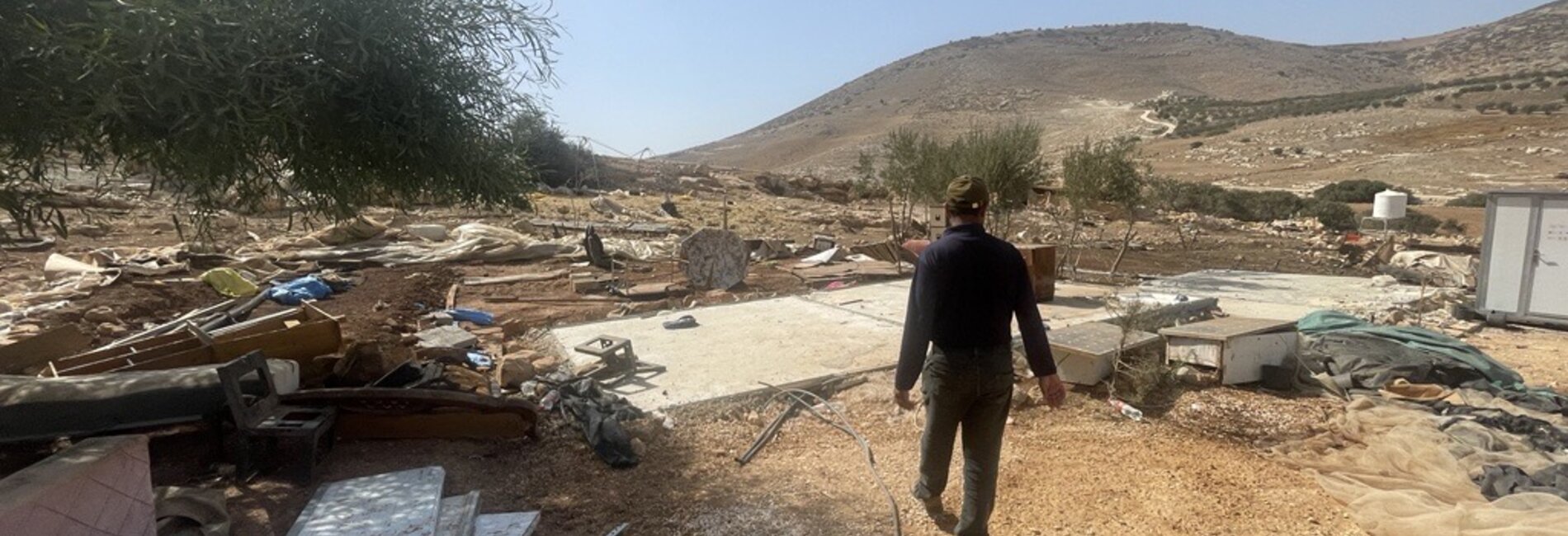 A Palestinian man walks by what remains of the structures that he and his neighbours had to dismantle in Ibziq herding community, in Tubas governorate, following a wave of settler attacks that has forced them to relocate. Photo by OCHA 