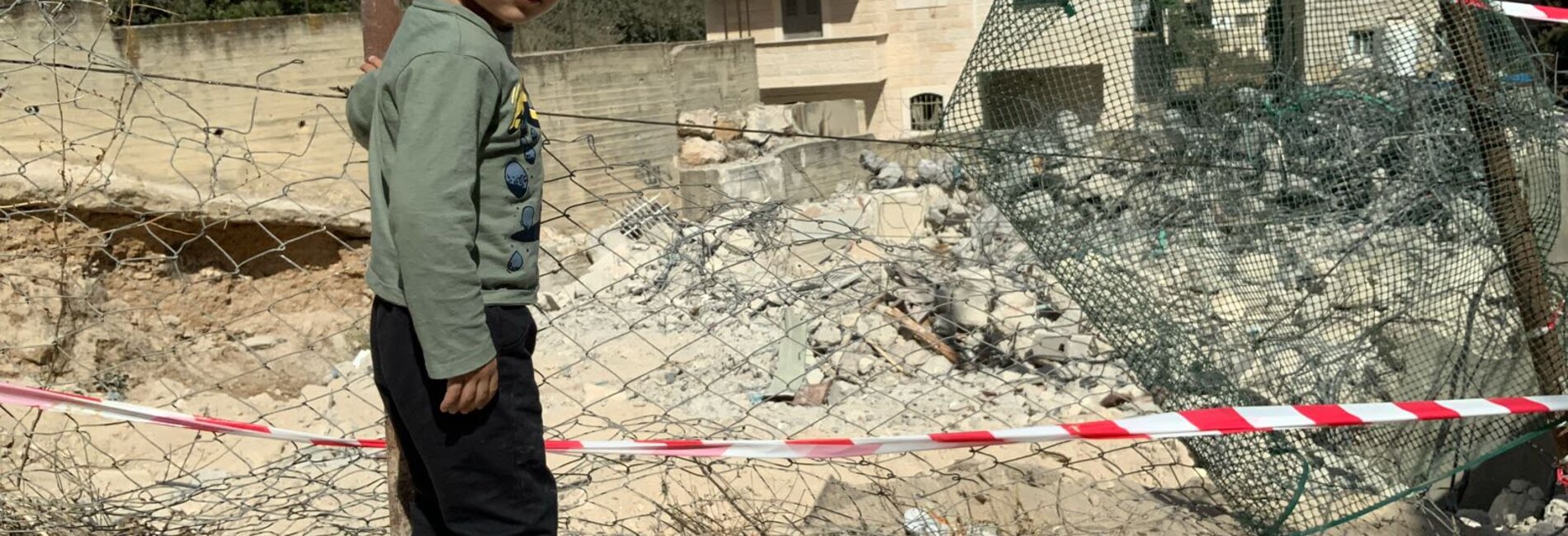 A displaced Palestinian boy next to what remains of his home that Israeli authorities forced his parents to demolish on 20 October, At Tur, East Jerusalem. Photo by OCHA
