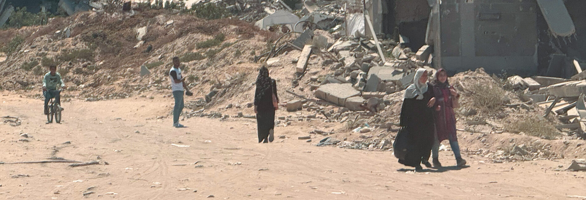 Palestinians in a destroyed area of Gaza, 4 June 2025. Photo by OCHA/Olga Cherevko