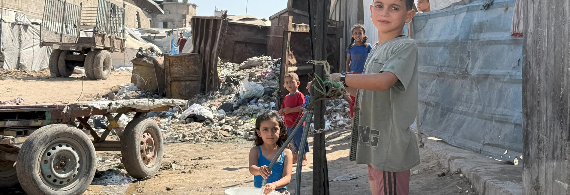Children fill buckets with water in Gaza city. Photo by OCHA/Olga Cherevko