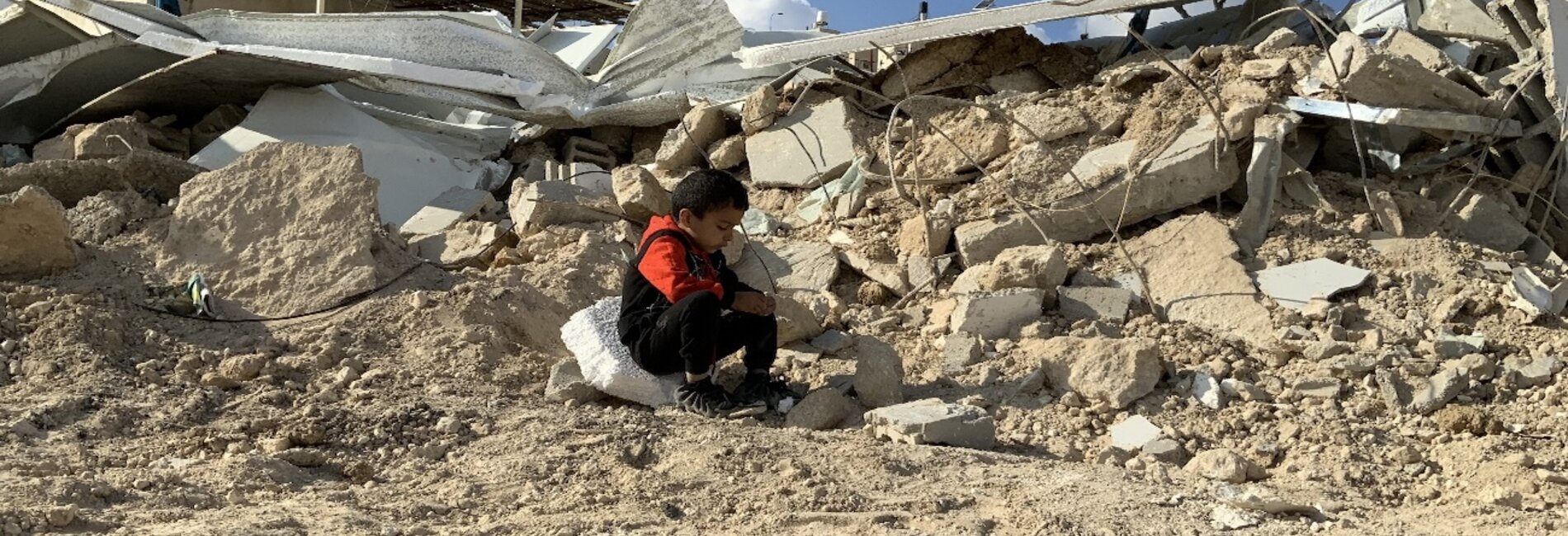 A Palestinian child sitting on the rubble of his families demolished house in Jabal Al Mukkabir, East Jerusalem. Photo by OCHA