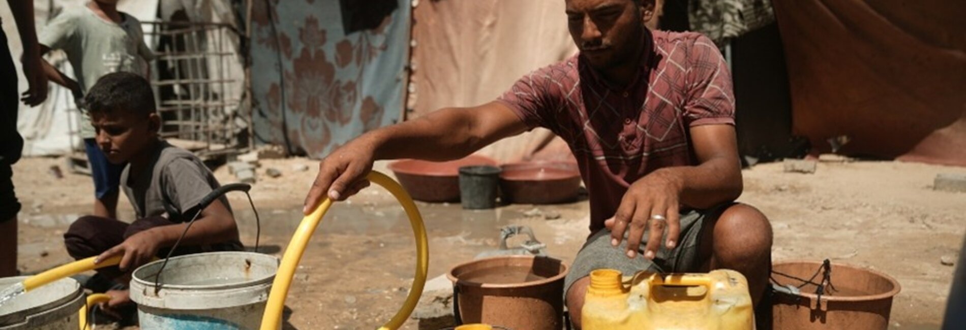 Jameel filling water containers at a displacement site in western Gaza in 2025. Photo by Mosab Alborno/Alef Multimedia, Oxfam, 22 September 2025.