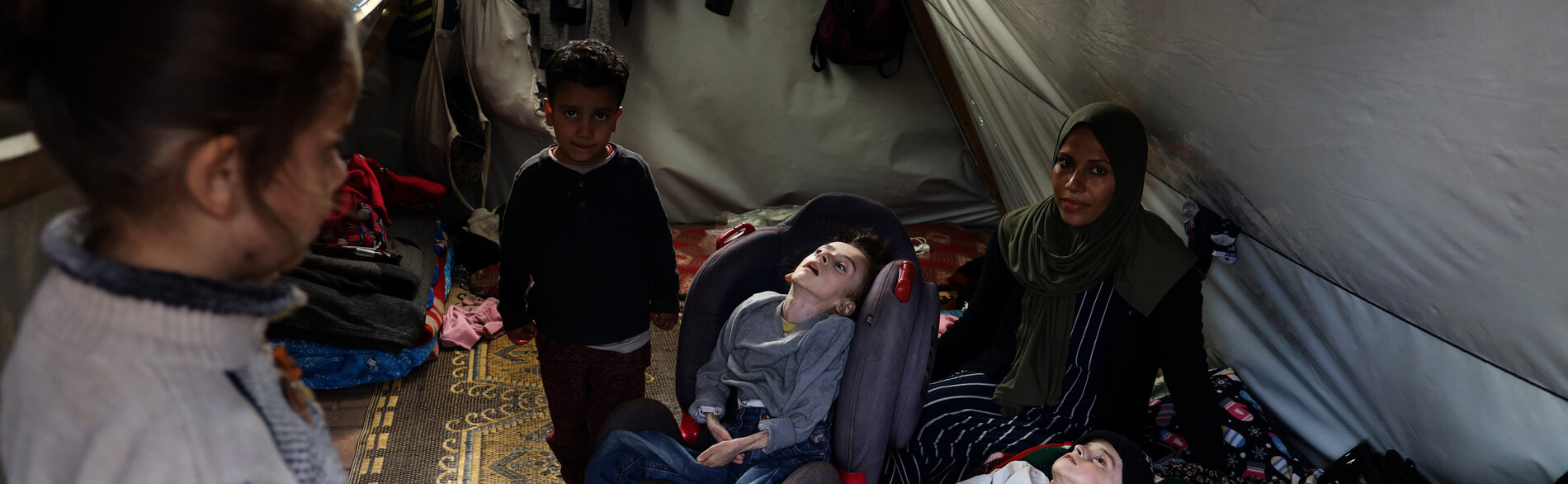 “None of the children has winter clothes. Four of us are sharing a single mattress… The little one sleeps in his carrier... They are all with diarrhea… It’s cold… Hatem has a cough. Their skin is peeling…” Mena, a single mother staying with her four children, including two with disabilities, in a makeshift tent in Al Quds Open University, Gaza. Photo by UNICEF/El Baba, 11 January 2024